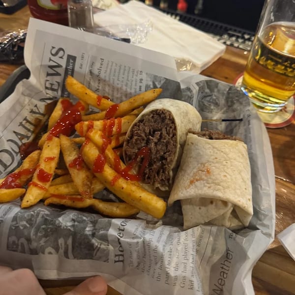 Two beef burritos and a side of ketchup-covered fries served on newspaper-lined tray at Gleason's Bar.