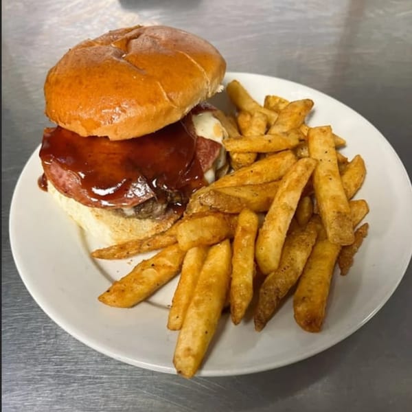 Gleasons Bar's American burger with barbecue sauce, cheese, and fries on a white plate.
